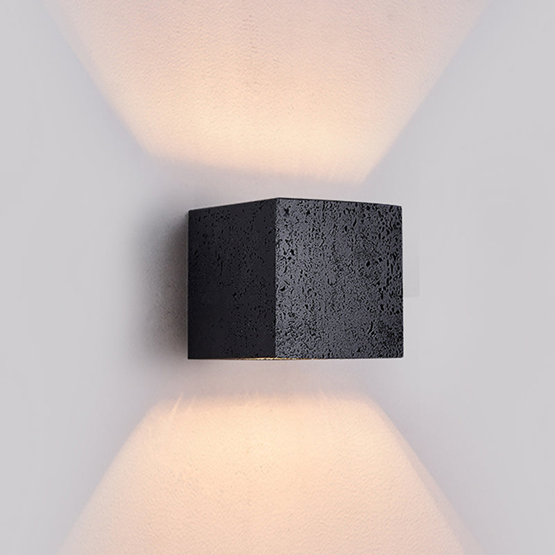 Modern wall-mounted light fixture with a textured black finish on a gray background