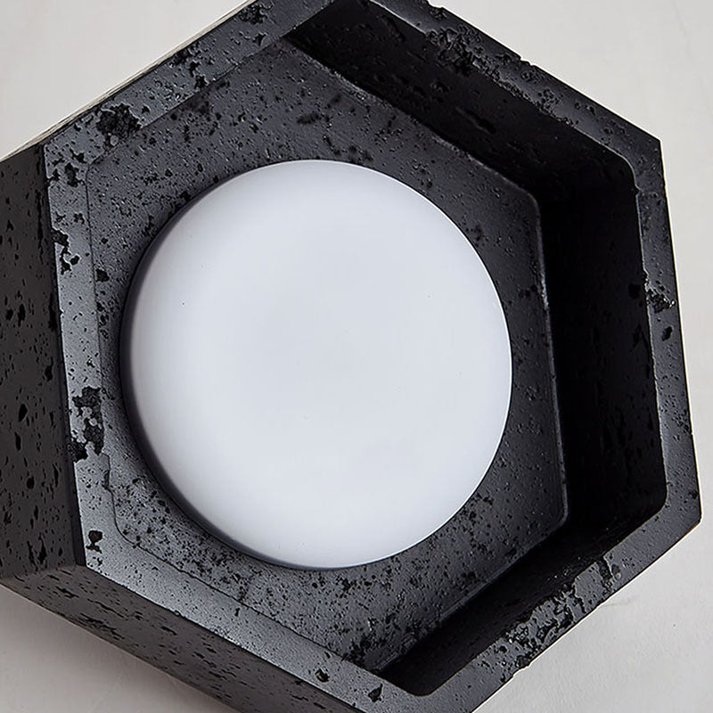 Hexagonal concrete light fixture with a white circular light bulb on a neutral background
