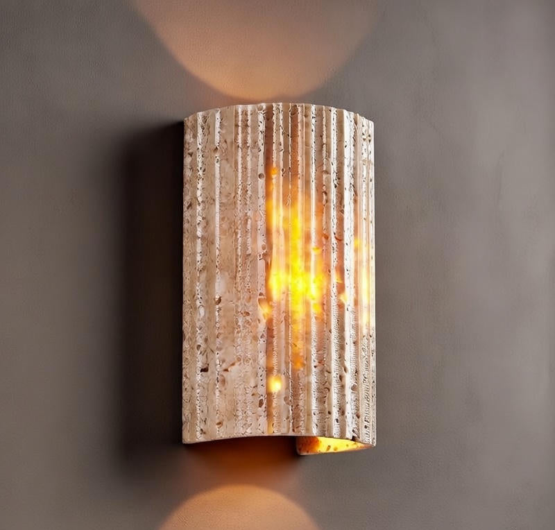 Decorative wall sconce with textured surface and warm glow on a gray background